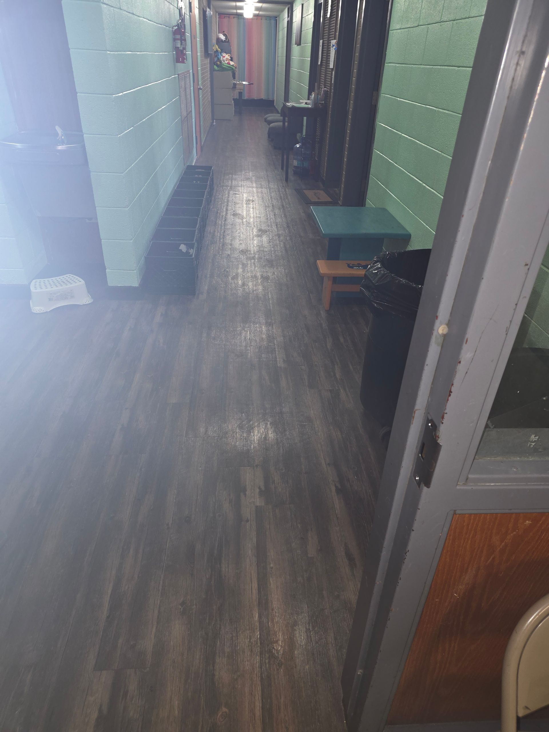 Narrow hallway with dark wood floor, green walls, and bench seating along the right side.