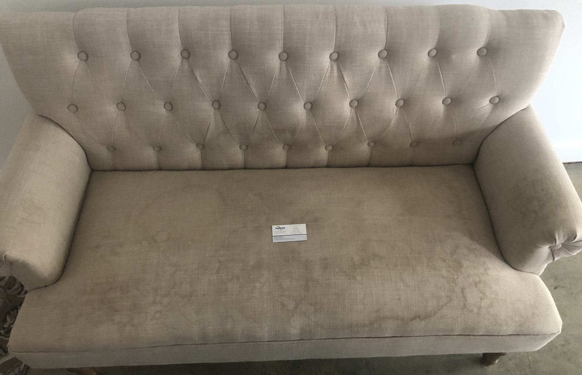 A beige couch is sitting on a carpet in a room.