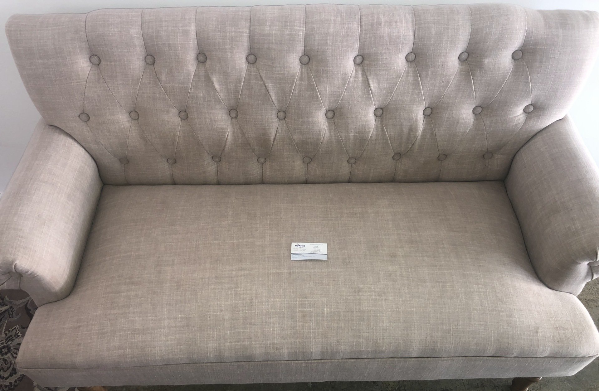 A beige couch is sitting in a living room next to a white wall.