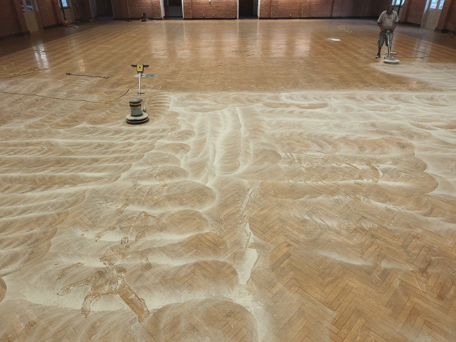 A man is cleaning a wooden floor with a vacuum cleaner.