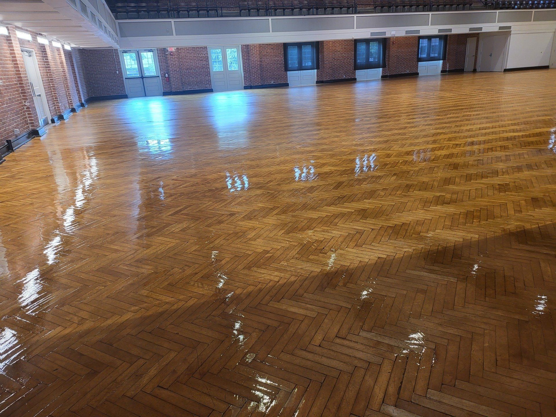 A large empty room with a wooden floor and brick walls.