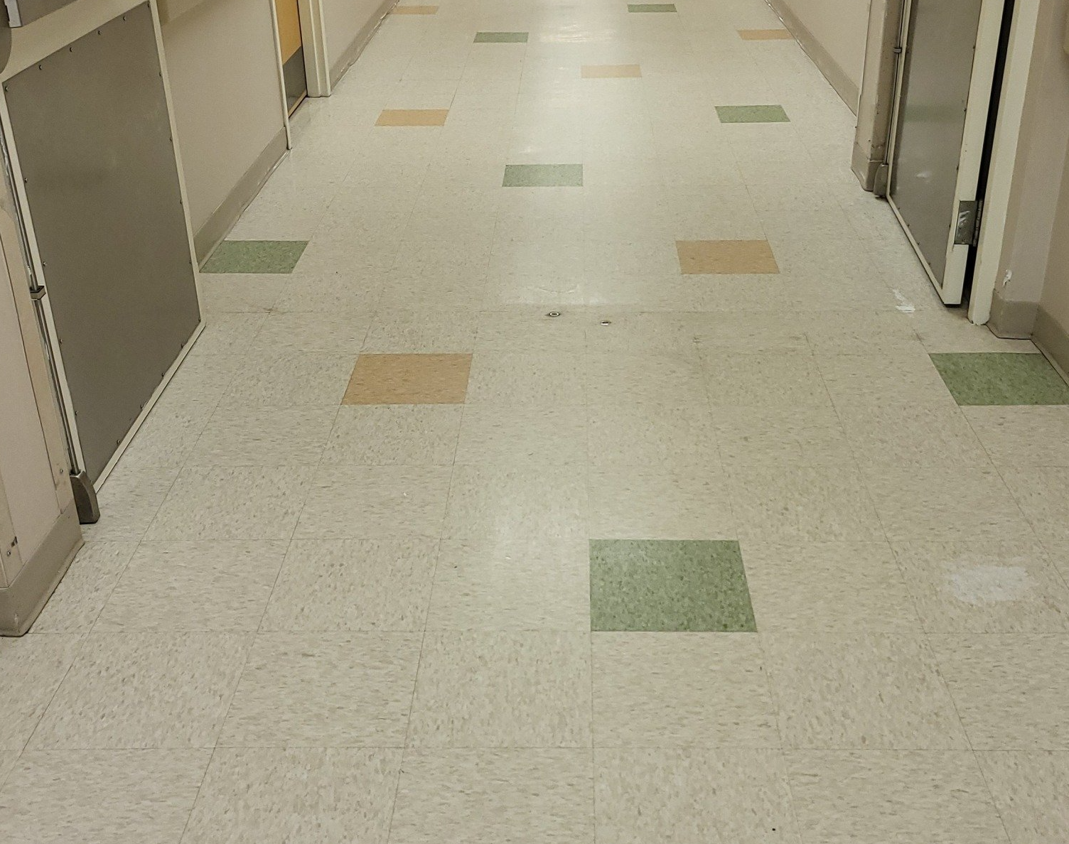 A hallway with a white tile floor and green and orange squares