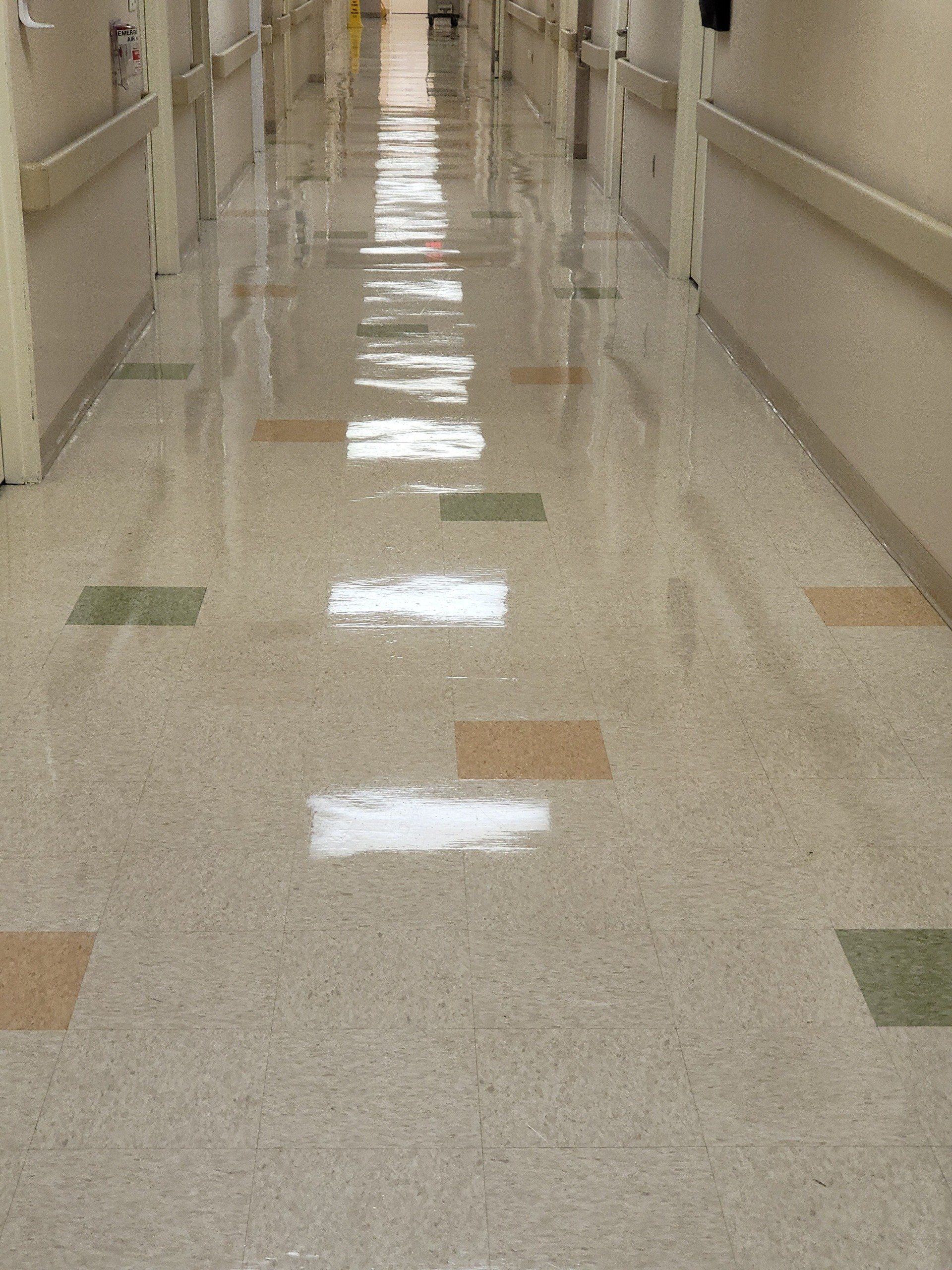 A long hallway in a hospital with a tiled floor