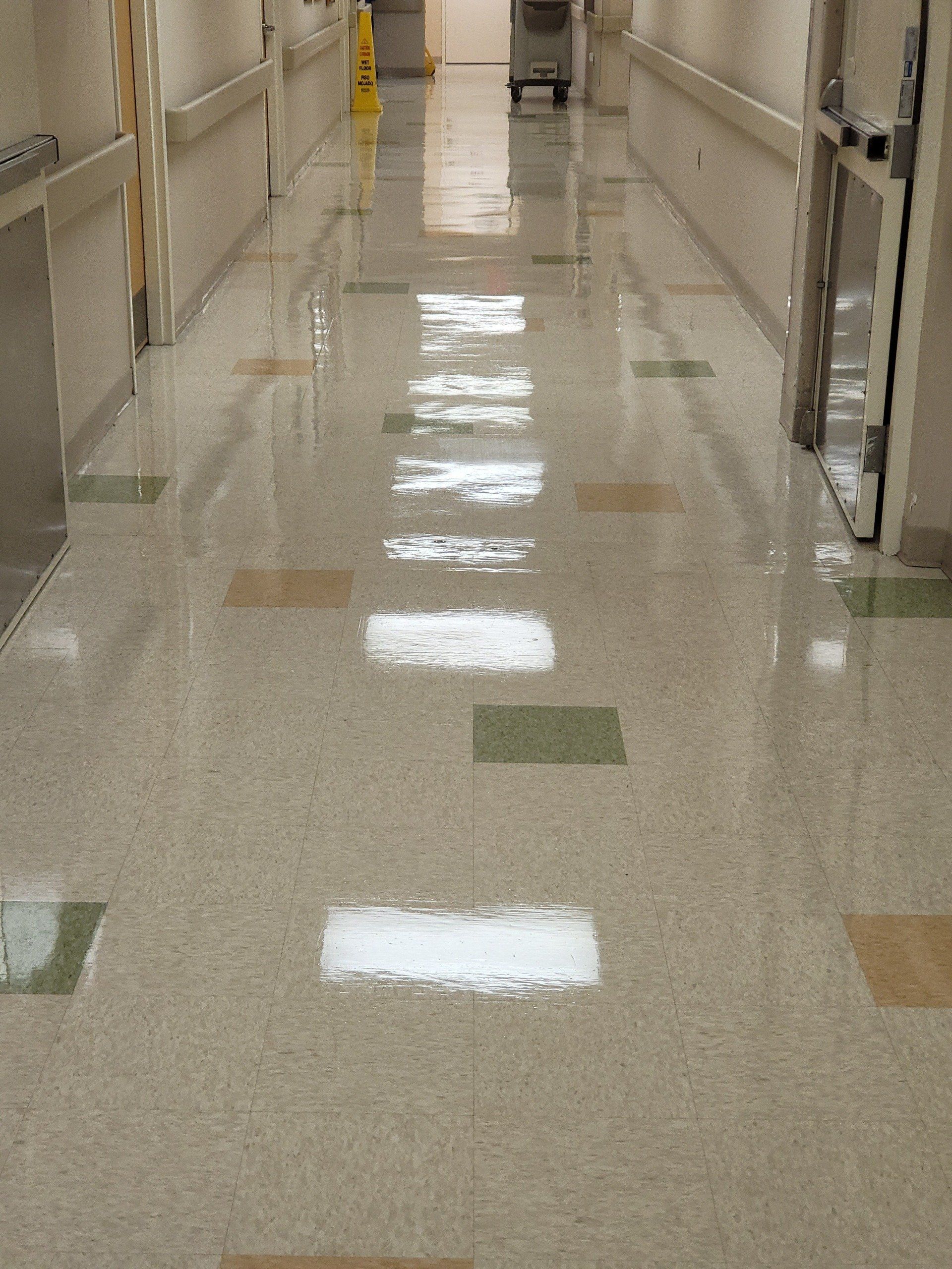A long hallway in a hospital with lots of lights on the floor.