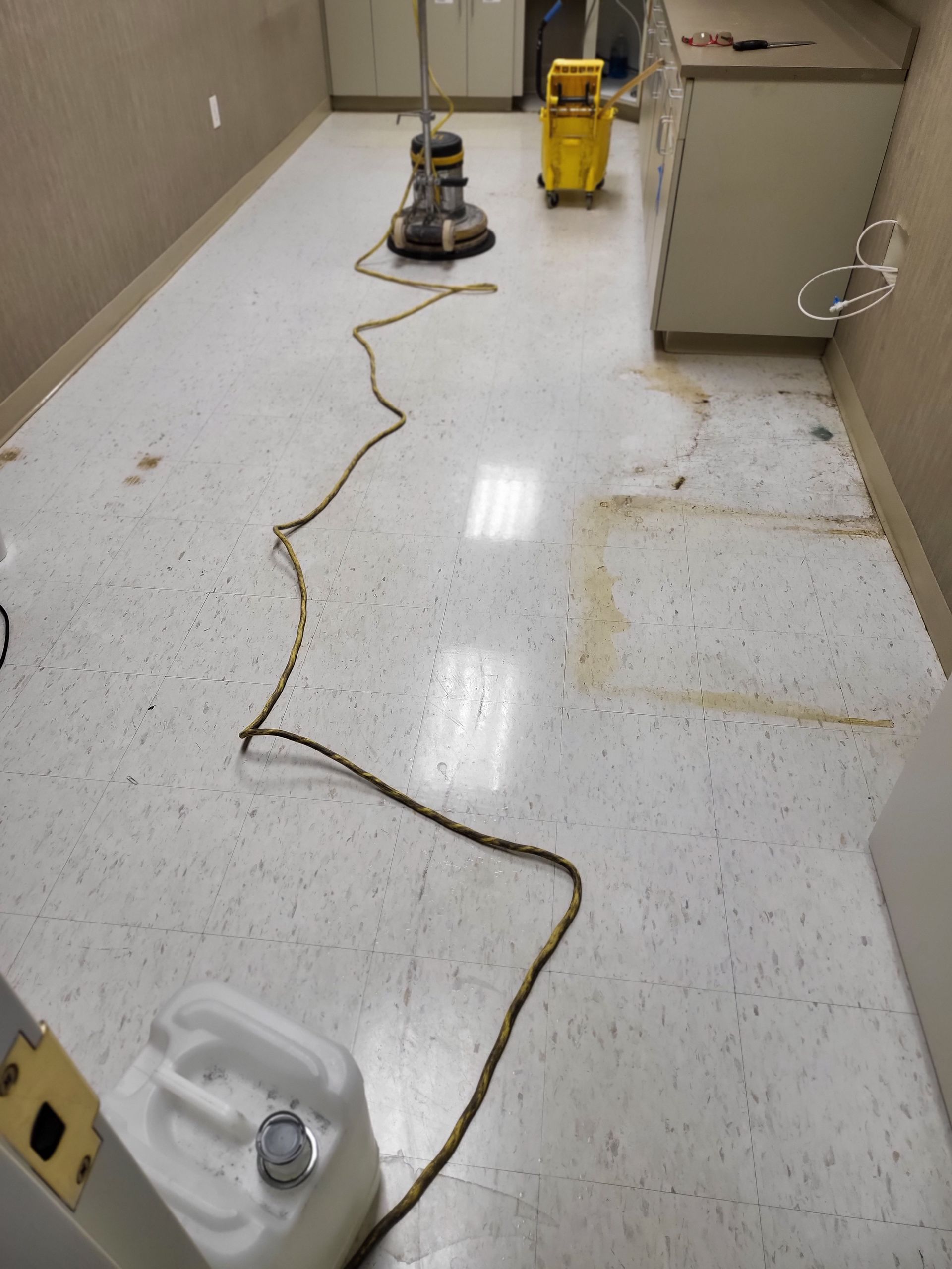 A vacuum cleaner is being used to clean a white tile floor