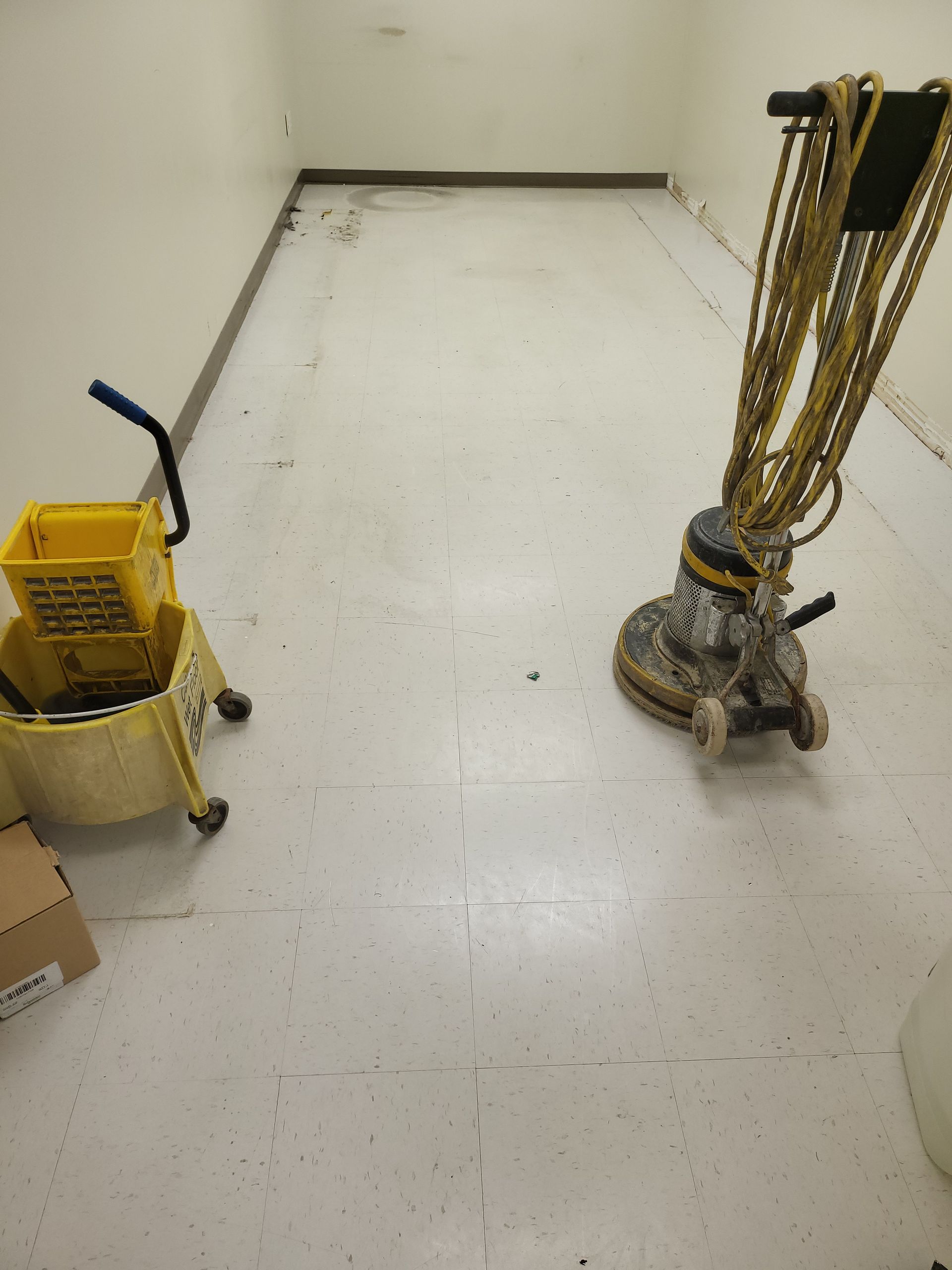 A yellow mop bucket sits next to a vacuum cleaner