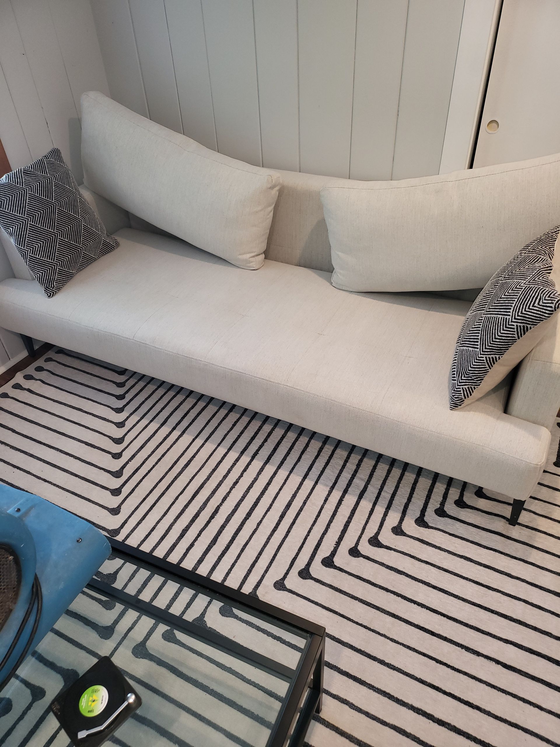 A white couch is sitting on a black and white rug