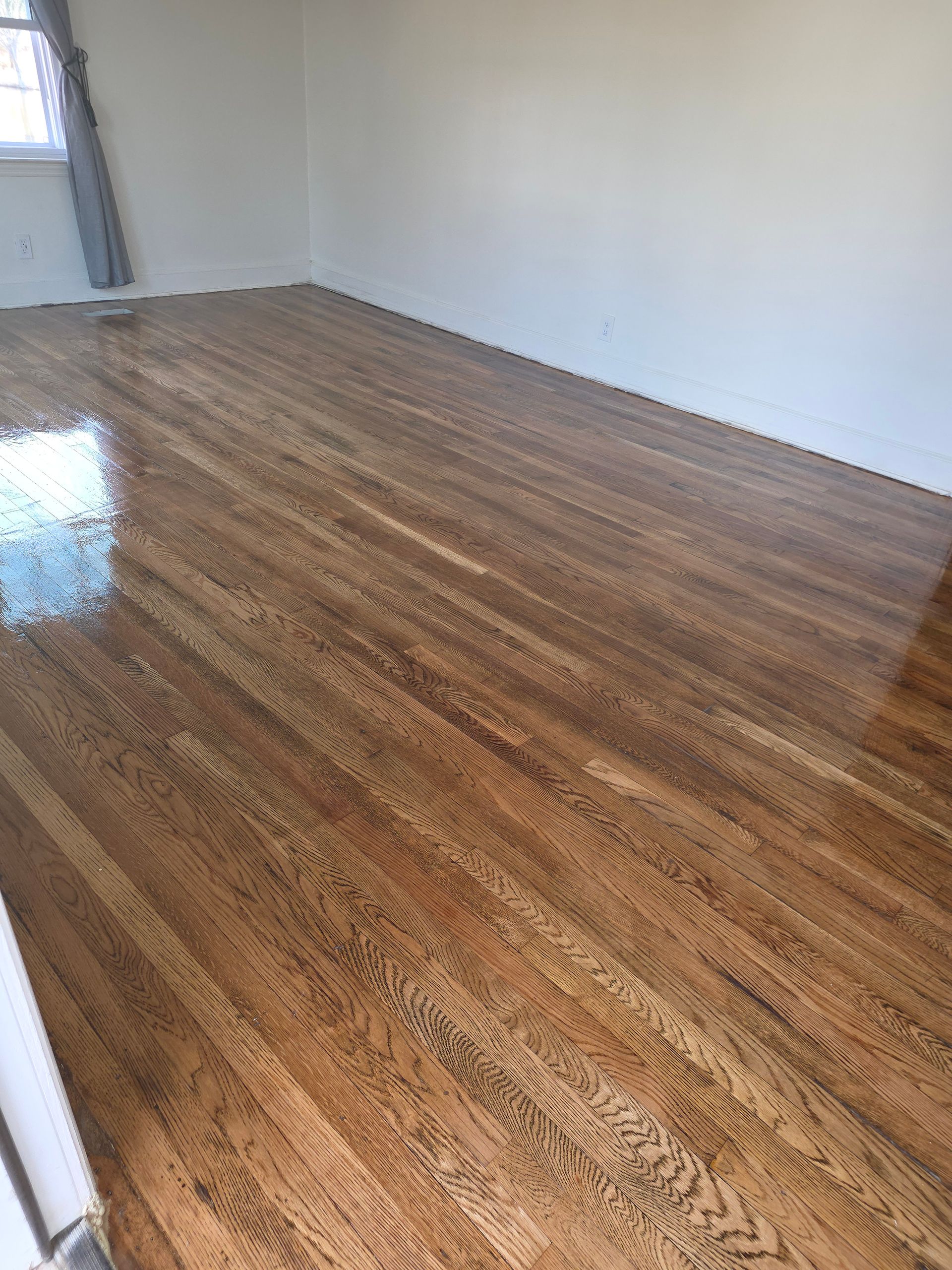 An empty living room with hardwood floors and a fireplace.