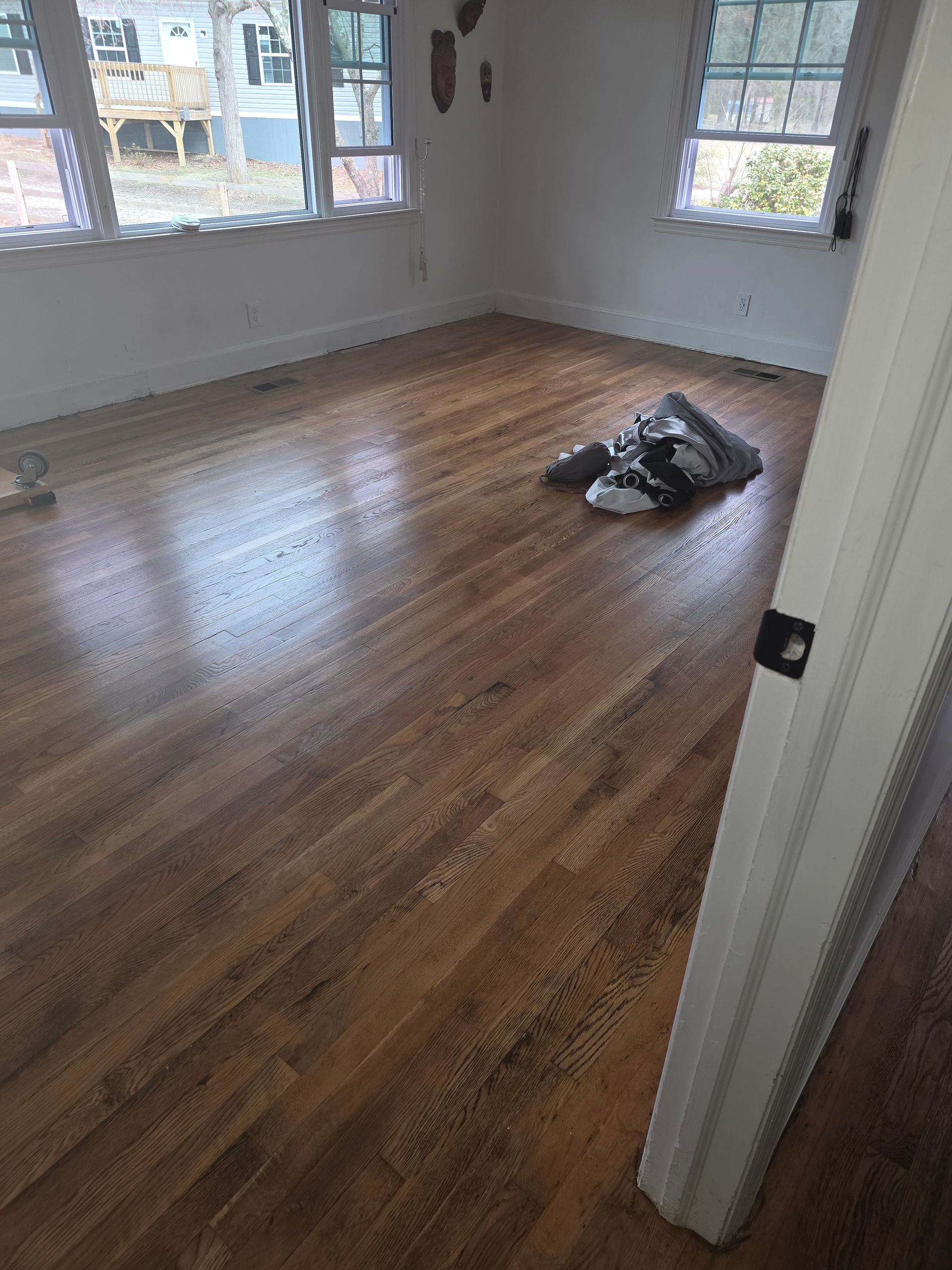 A living room with hardwood floors and a fan in the background.