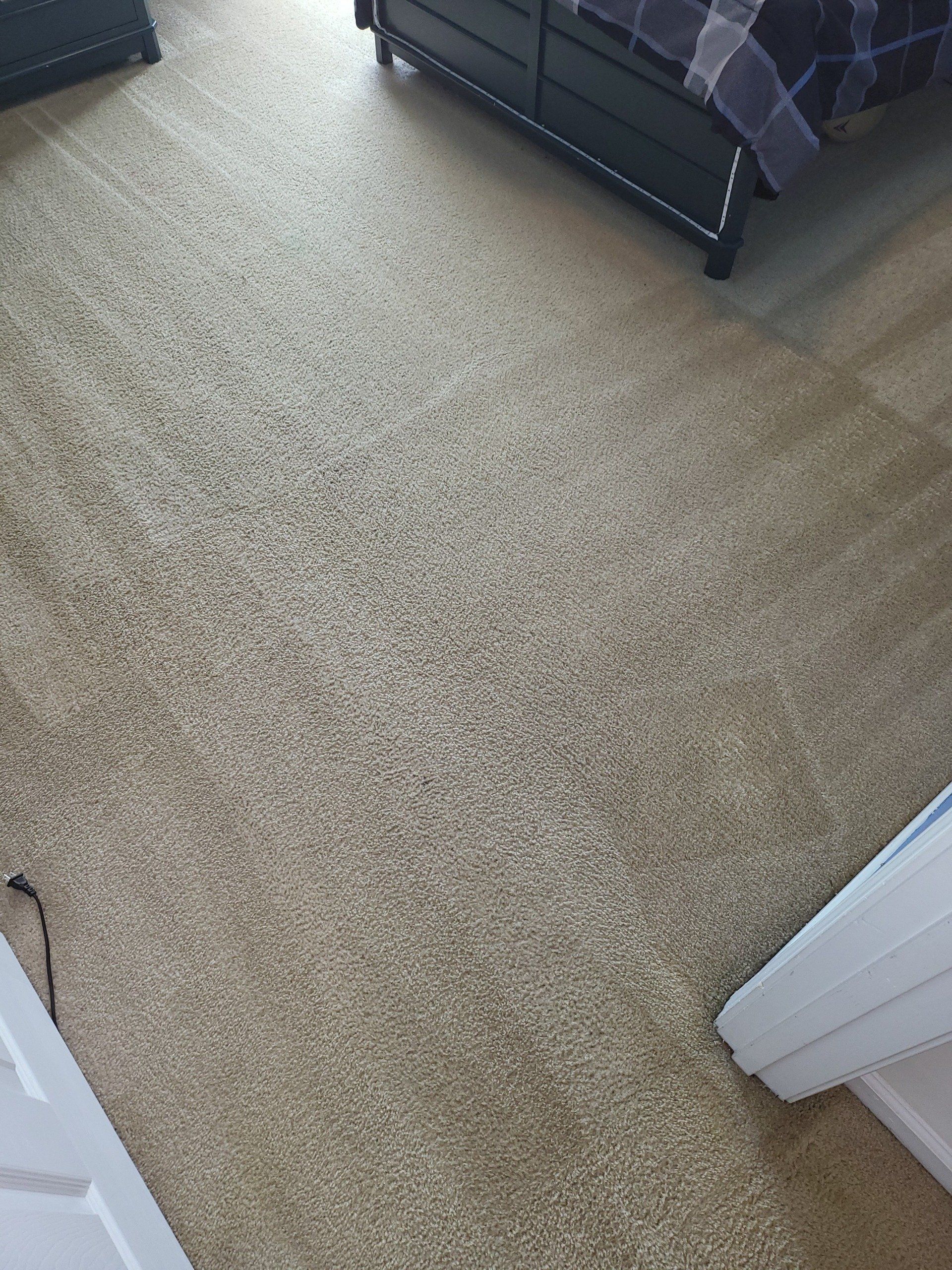 A bedroom with a carpeted floor and a bed.