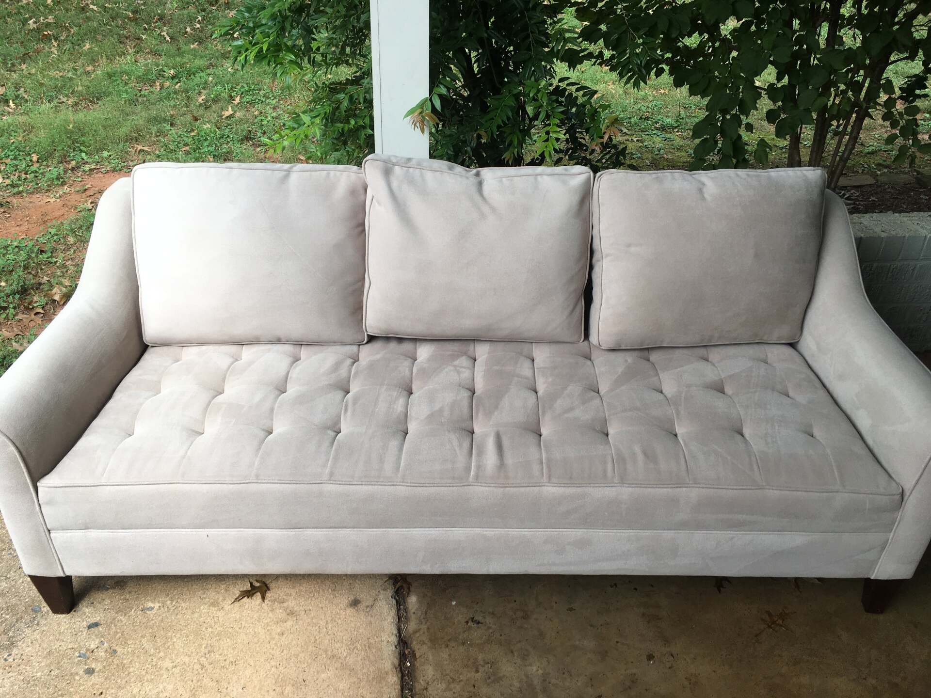 A white couch is sitting outside on a porch