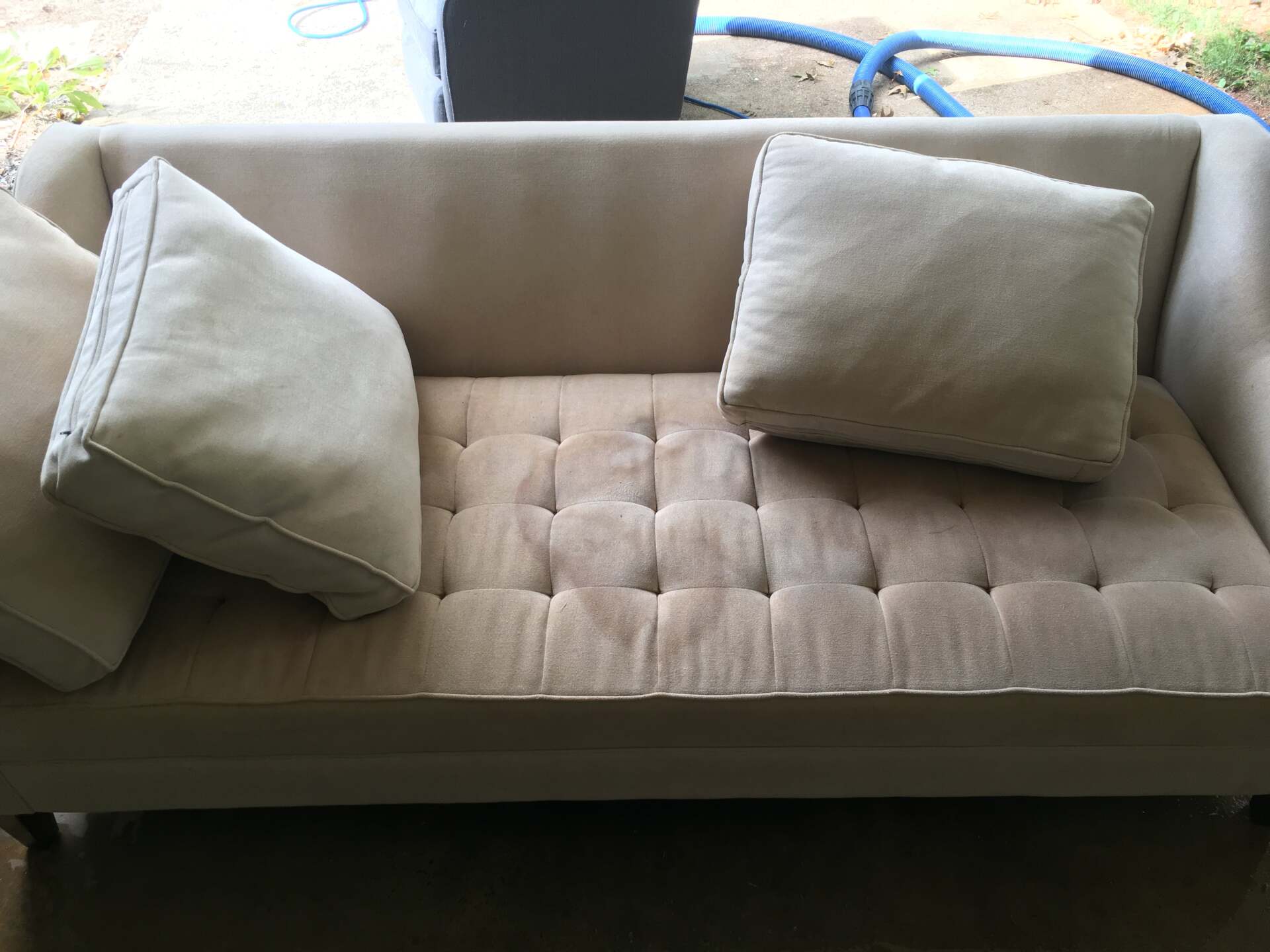 A beige couch with white pillows on it