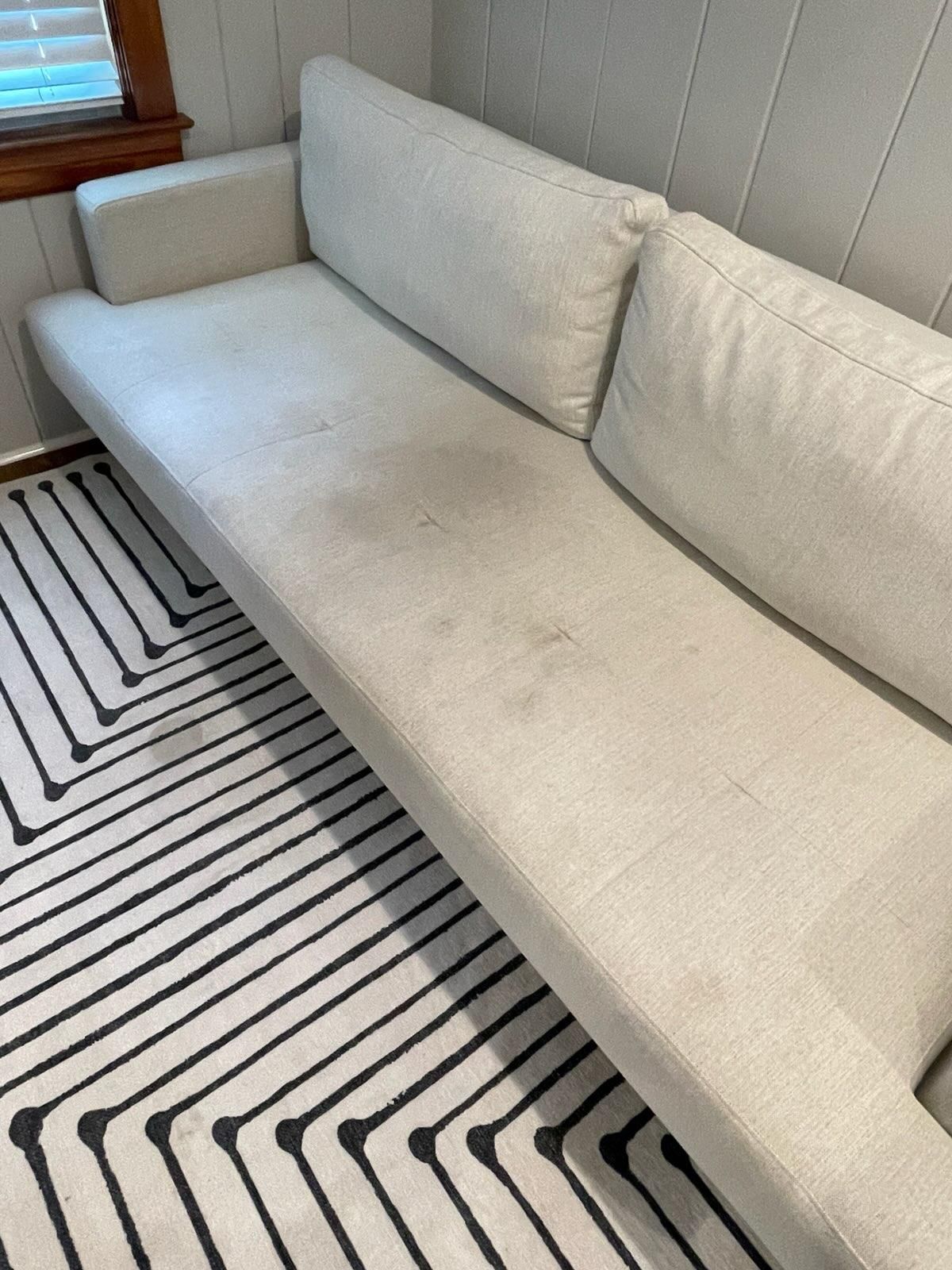 A white couch is sitting on a black and white rug in a room.