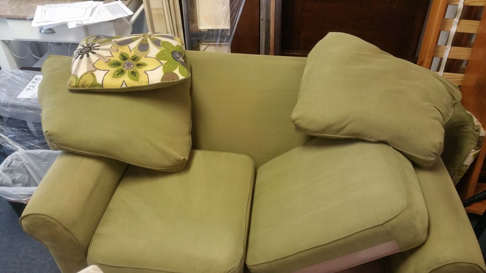 A green couch with a pillow on top of it