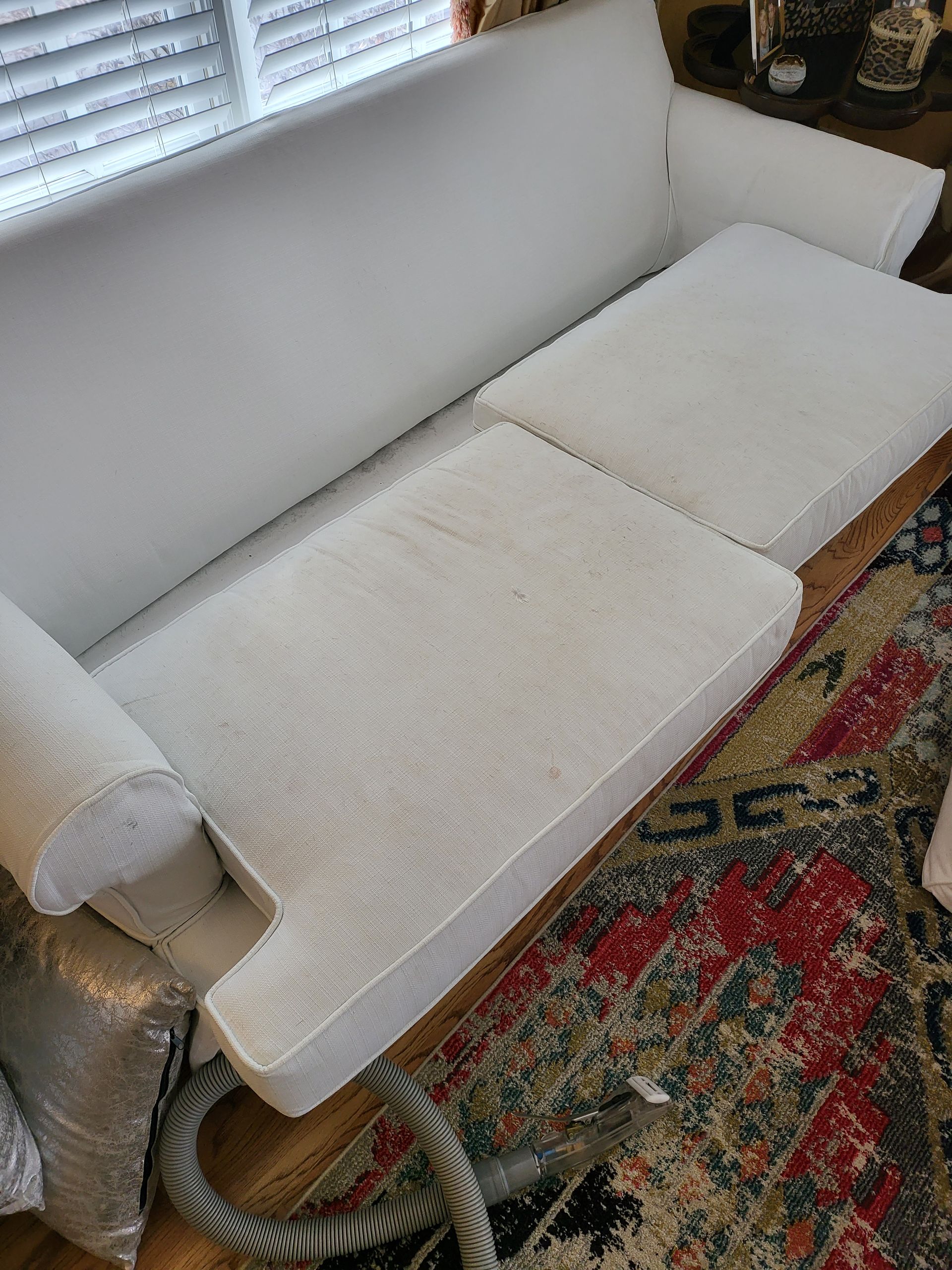 A white couch is sitting on a rug next to a window.