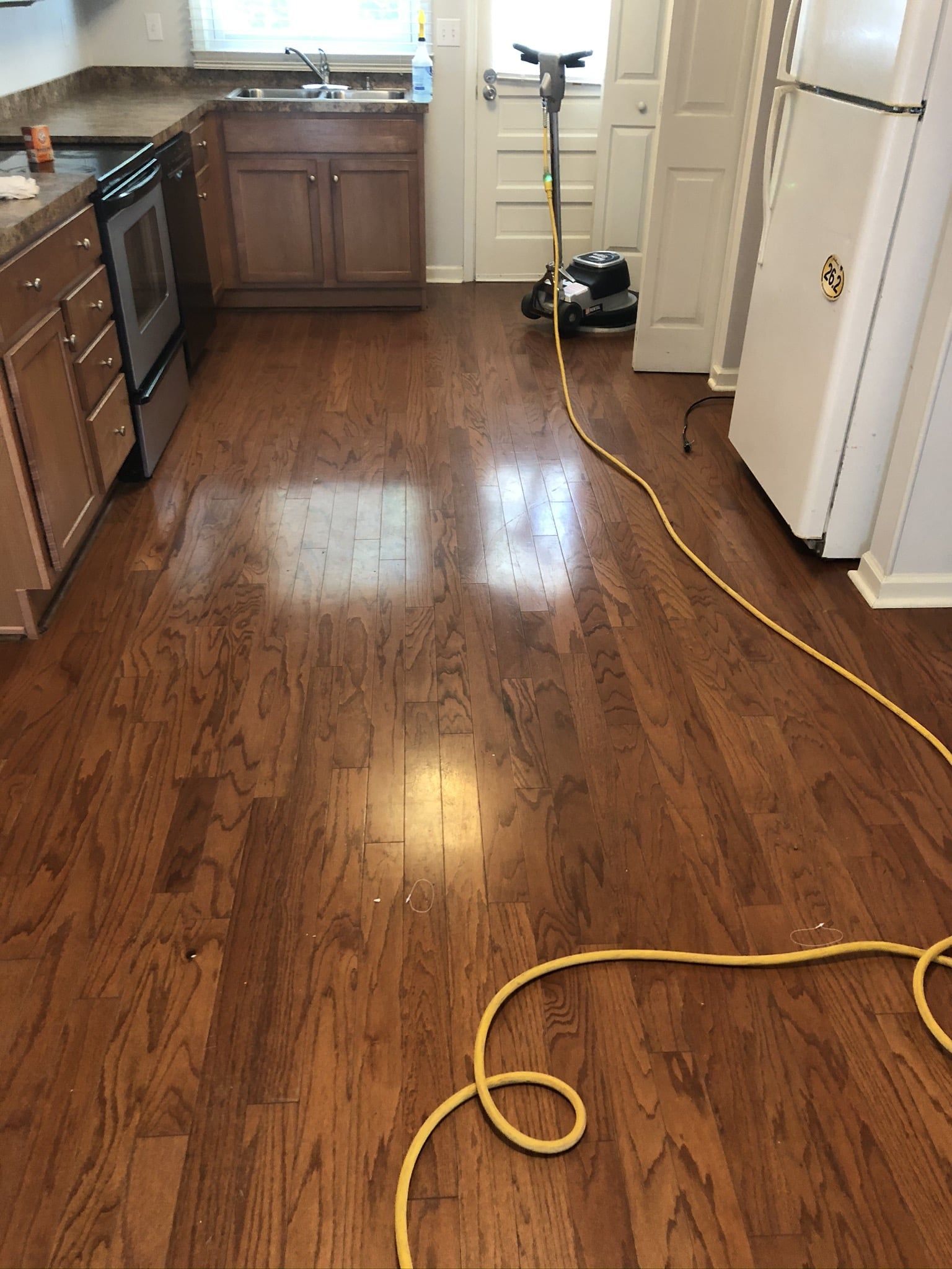 A kitchen with hardwood floors and a vacuum cleaner on the floor.