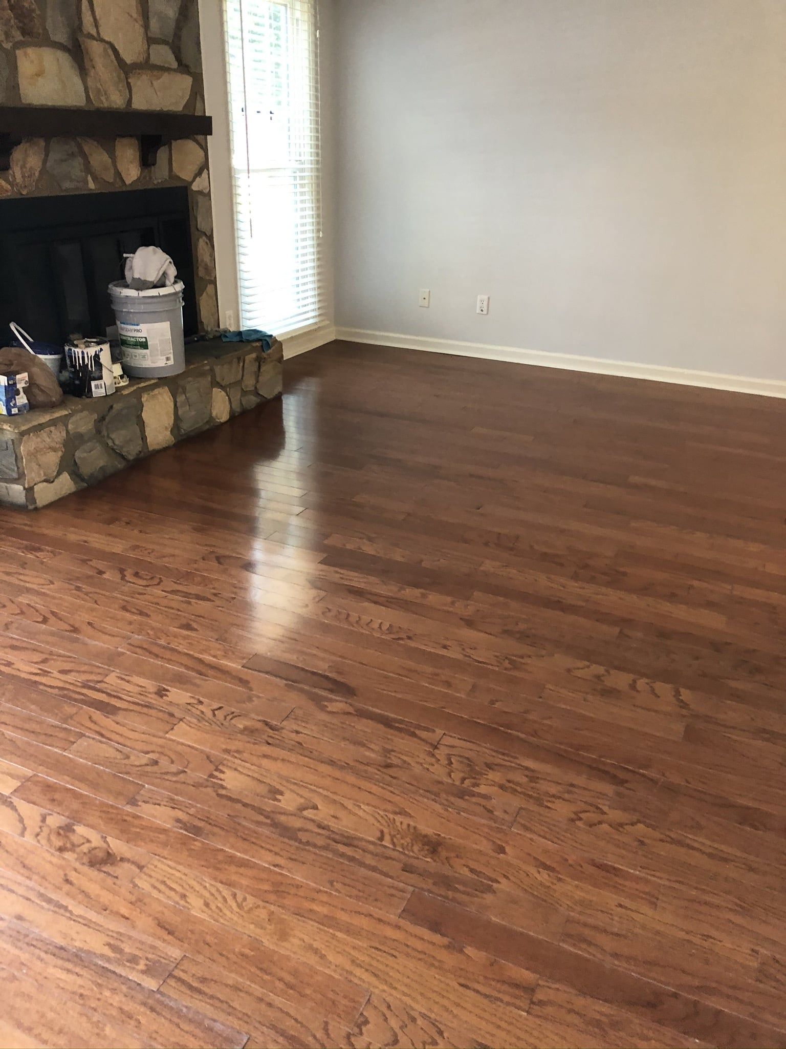 An empty living room with hardwood floors and a fireplace.