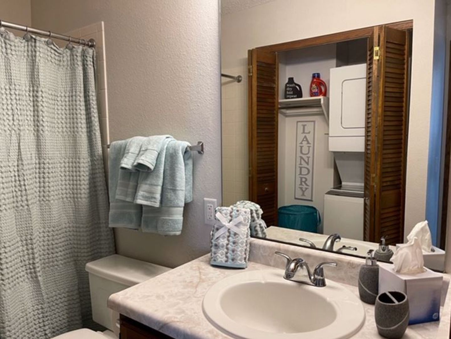 a bathroom with a sink , toilet , shower and laundry closet