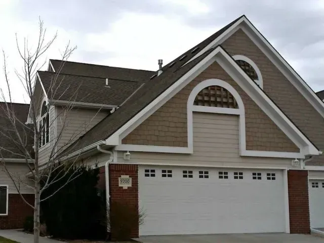a house with a triangle shaped roof and a white garage door
