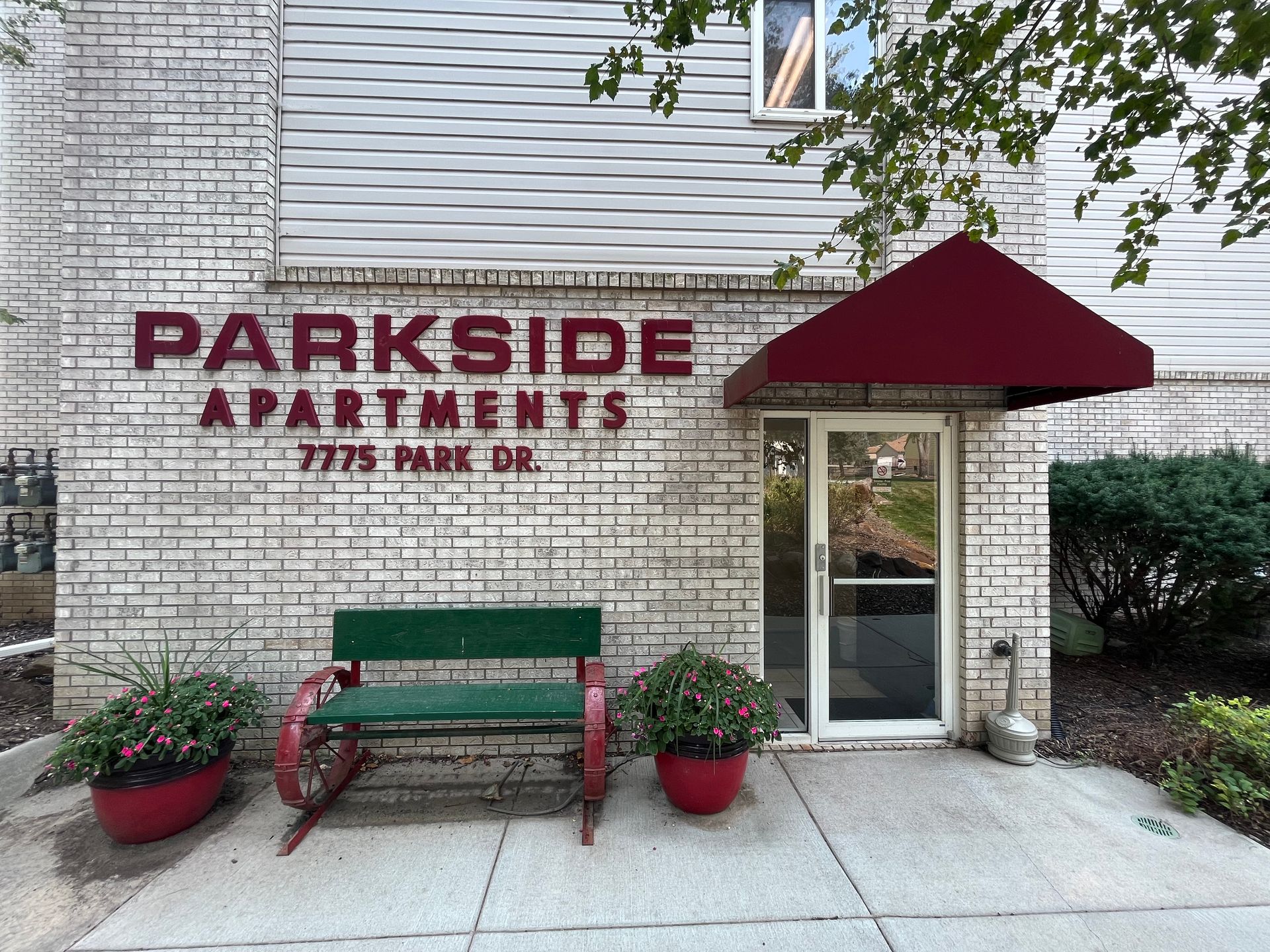 a parkside apartments building with a green bench in front of it