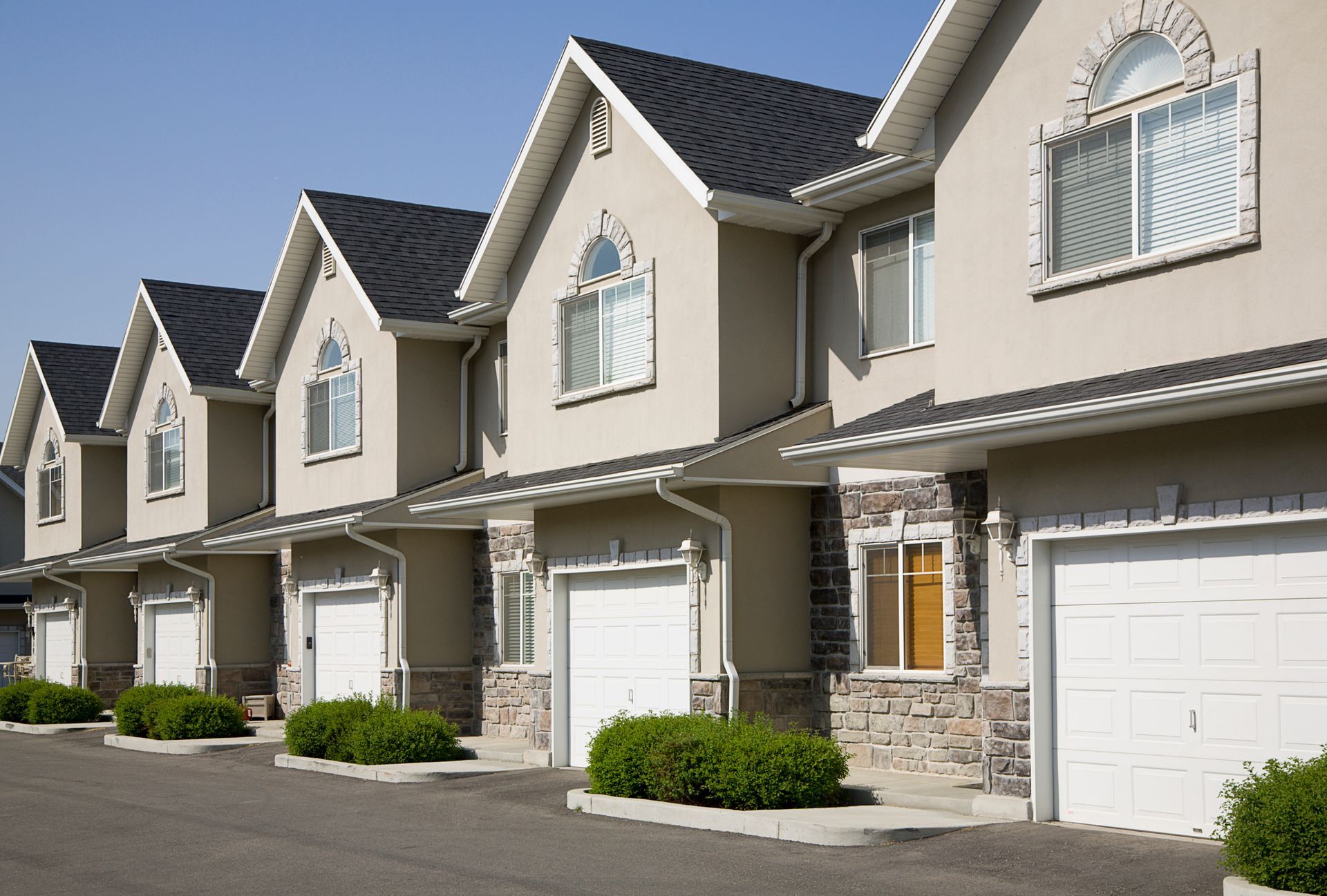 a row of apartment buildings with white garage doors