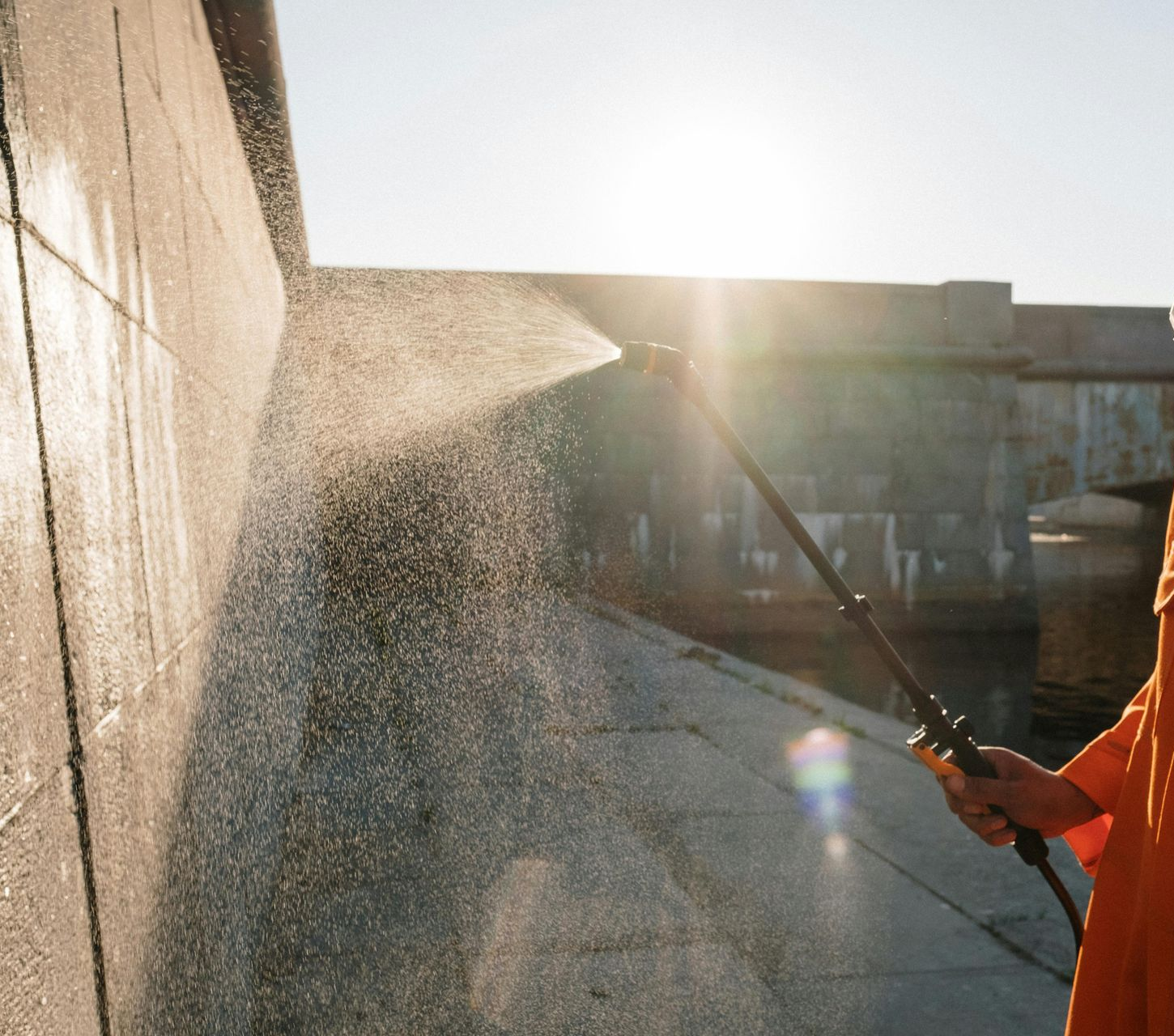man pressure washing exterior of building