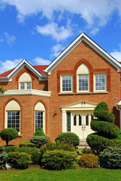 pristine brick home with beautiful residential landscaping out front