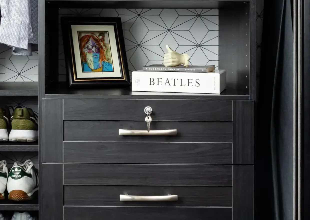 Dark dresser shelf with framed art, a white Beatles box, and a small figurine