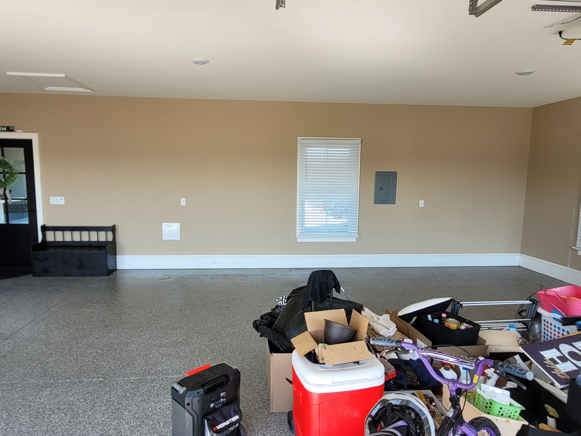 Spacious empty garage with beige walls and cluttered storage items in the foreground