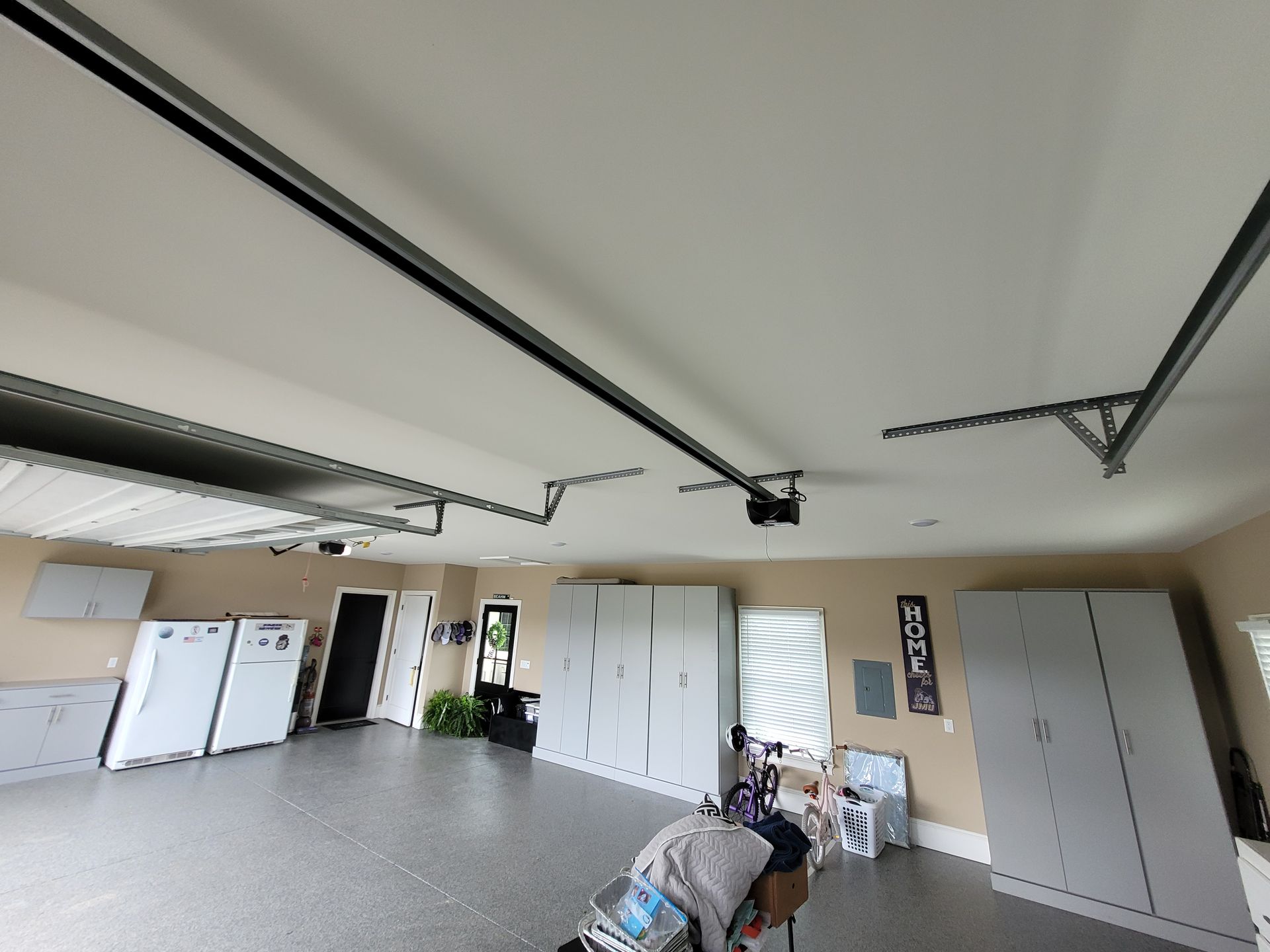 Spacious garage with white cabinets, storage racks, a workbench, and a closed overhead door.