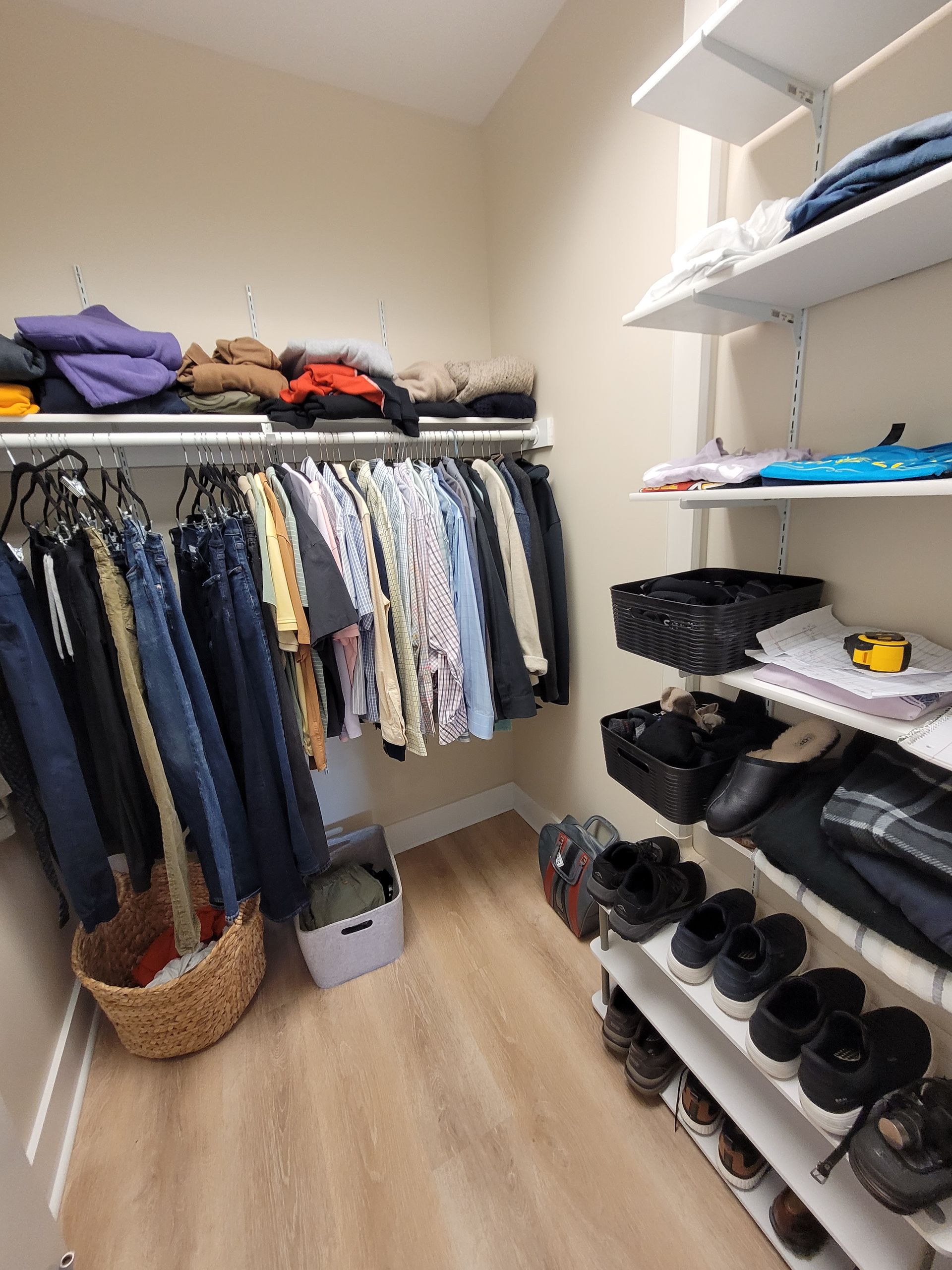 Walk-in closet with hanging clothes, folded items, and shelves of shoes and boxes