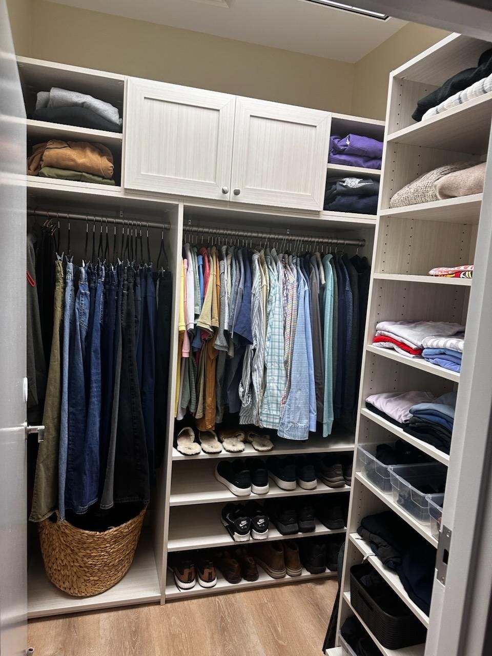 Walk-in closet with hanging clothes, folded items on shelves, baskets, and shoe racks.