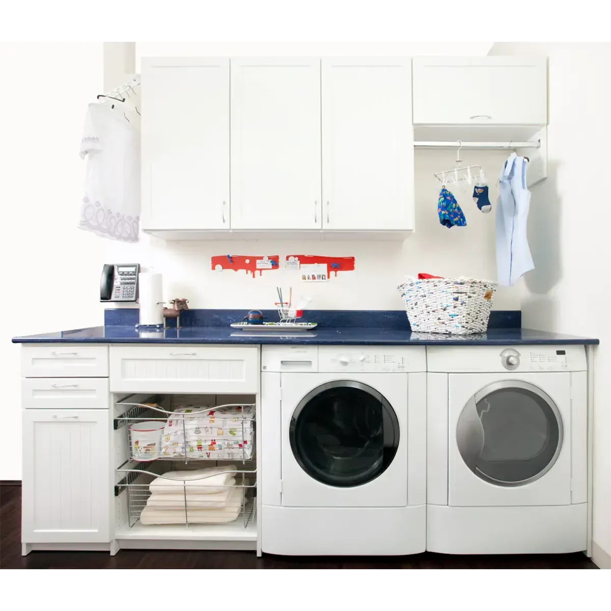 Bright white laundry room with washer, dryer, sink cabinet, and storage cabinets.