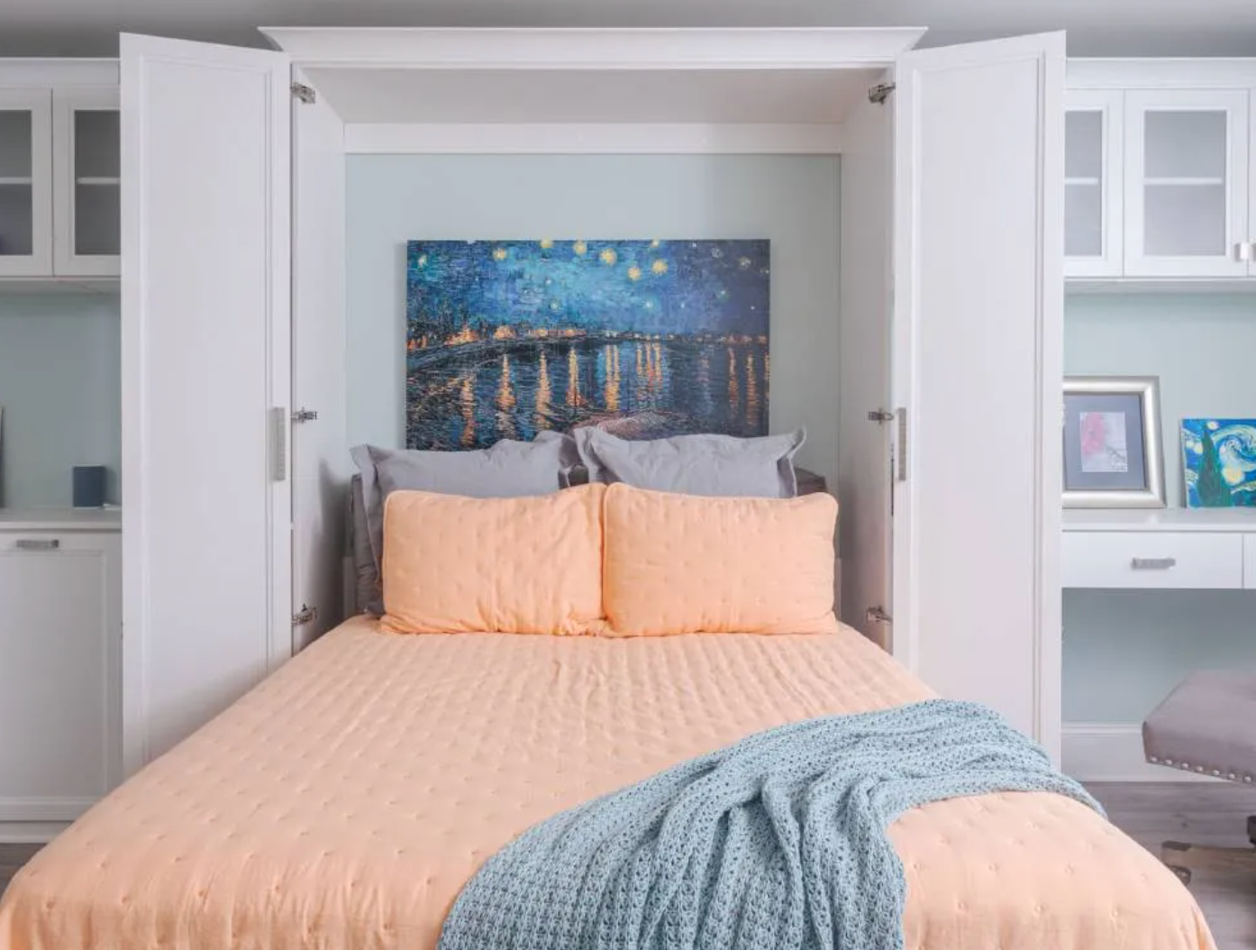 Neatly made bed with peach bedding and blue throw in a bright built-in alcove bedroom
