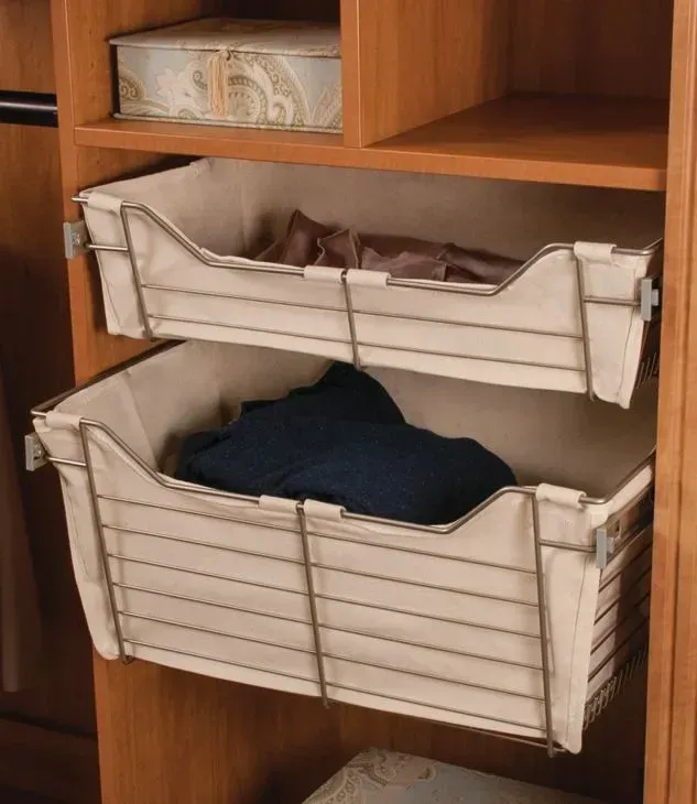 Wooden closet with two cream fabric pull-out drawers, one holding folded clothes and the other blue fabric.