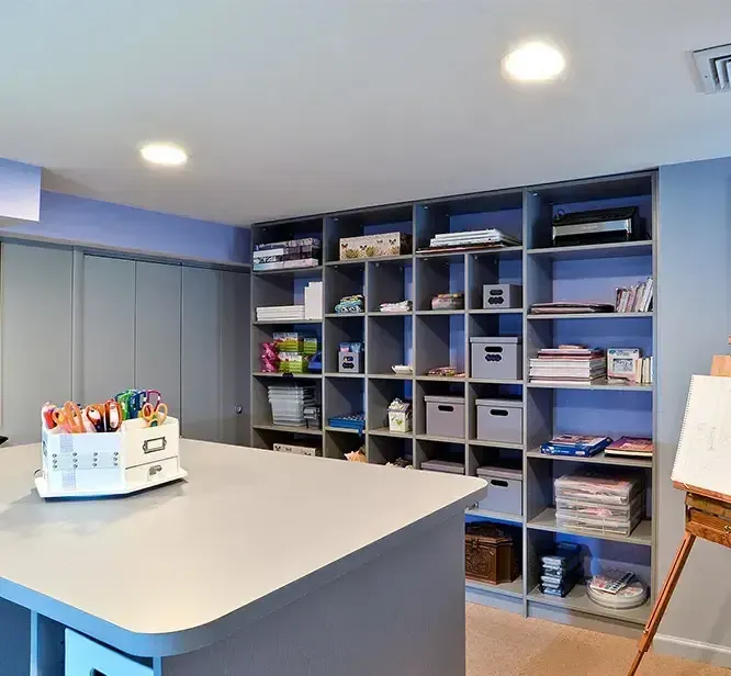 Bright craft room with blue cubbies, white table, and easel under recessed ceiling lights