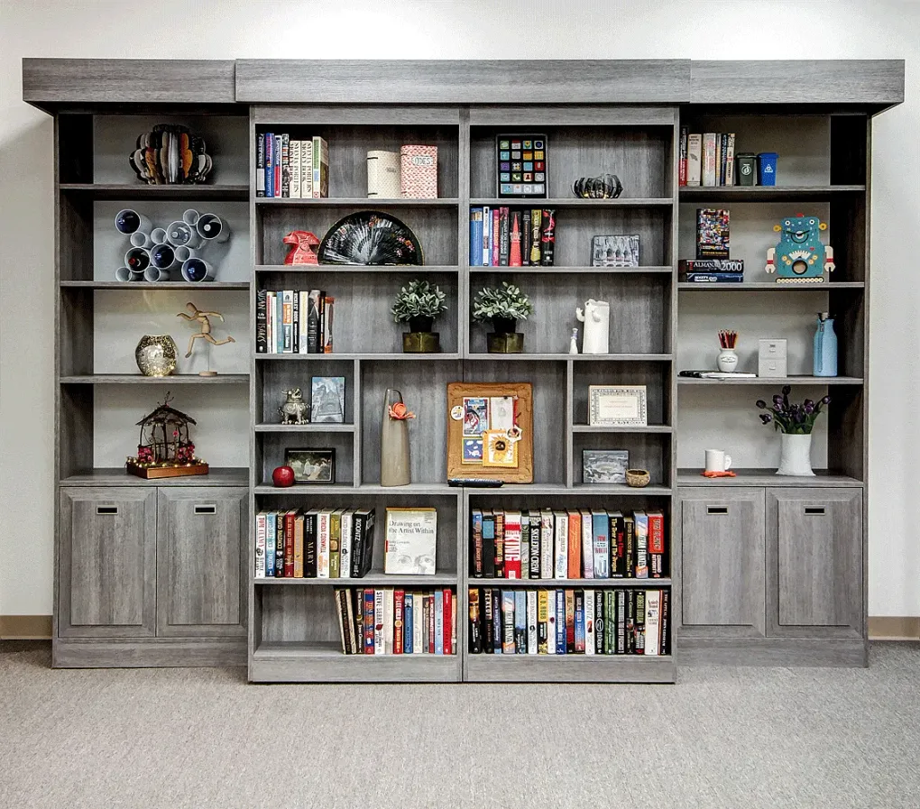 Large gray built-in shelving unit filled with books, decor, and collectibles in a carpeted room