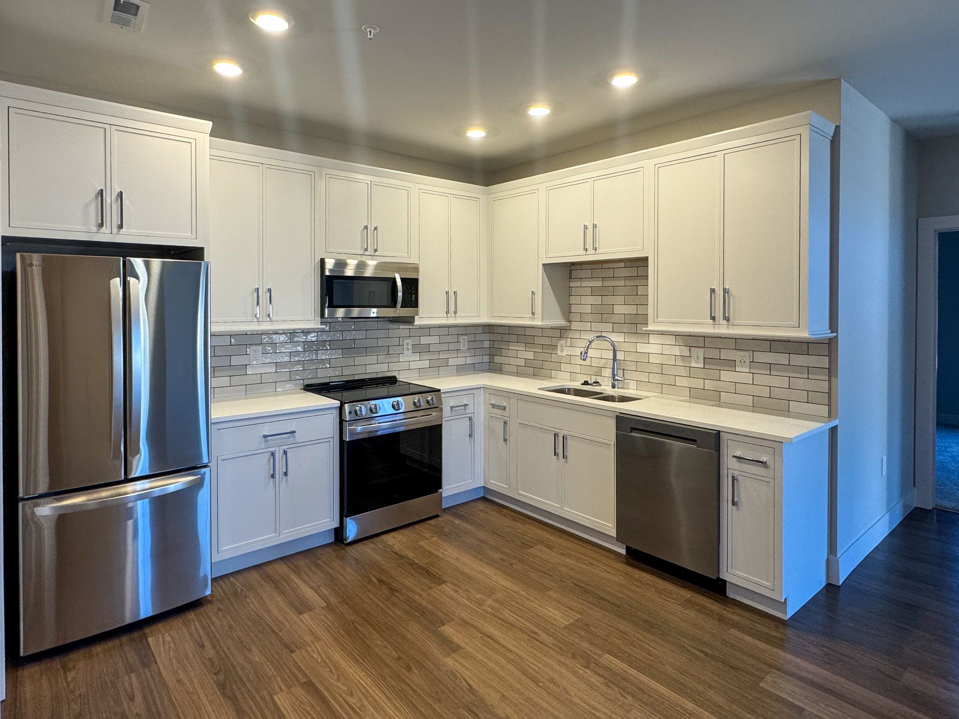 Modern kitchen with white cabinets, stainless steel appliances, and a tile backsplash.