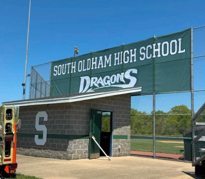 South Oldham High School entrance sign with “Dragons” above a brick gate and open field behind it