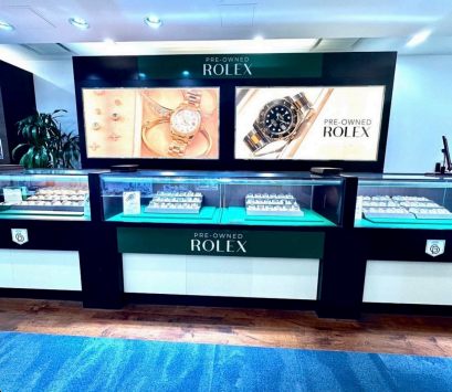 Rolex watch display counter with illuminated showcases and promotional panels in a luxury store