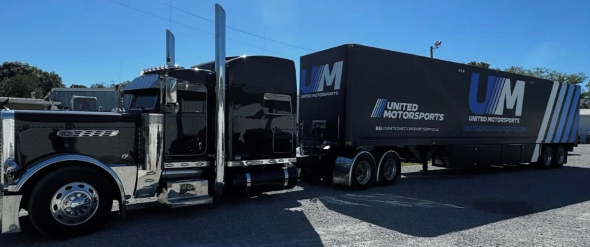 Black semi-truck hauling a United Road Services trailer parked outdoors in daylight