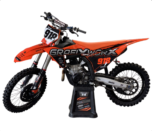 Orange and black GroovyWorks dirt bike on a stand, side view with knobby tires and number 918