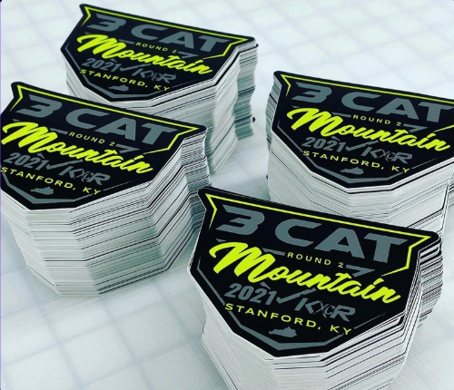 Stacks of CAT Mountain 2021 Stanford, KY stickers on a white surface