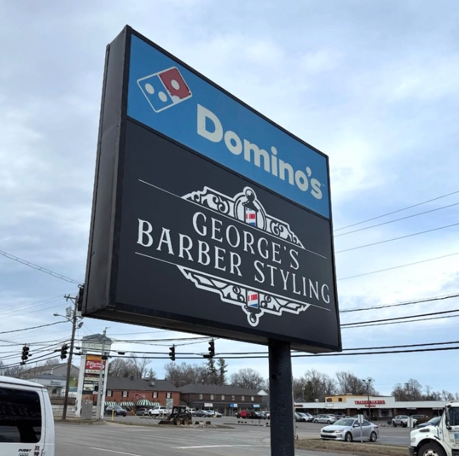 Domino’s and George’s Barber Styling roadside sign on a cloudy street corner