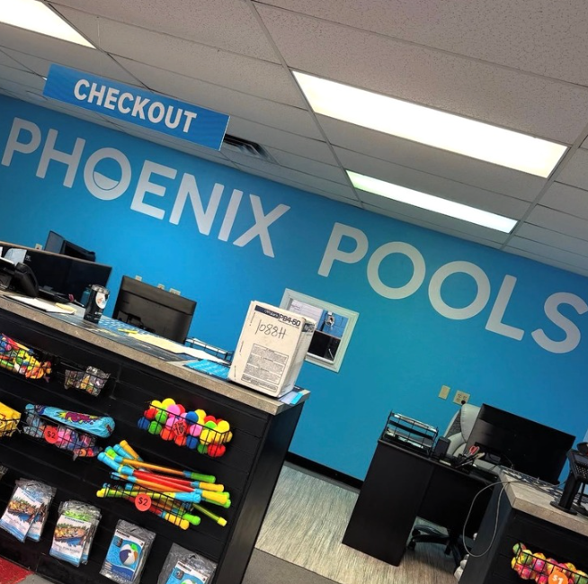 Checkout area inside Phoenix Pools store with blue wall, counters, and colorful pool toys on display.