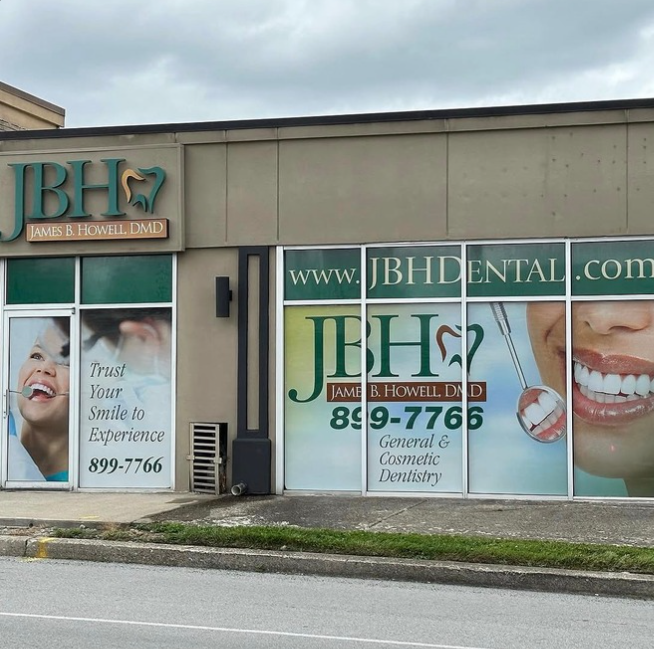 Dental office storefront with J&H Dental signage and large smiling teeth graphics