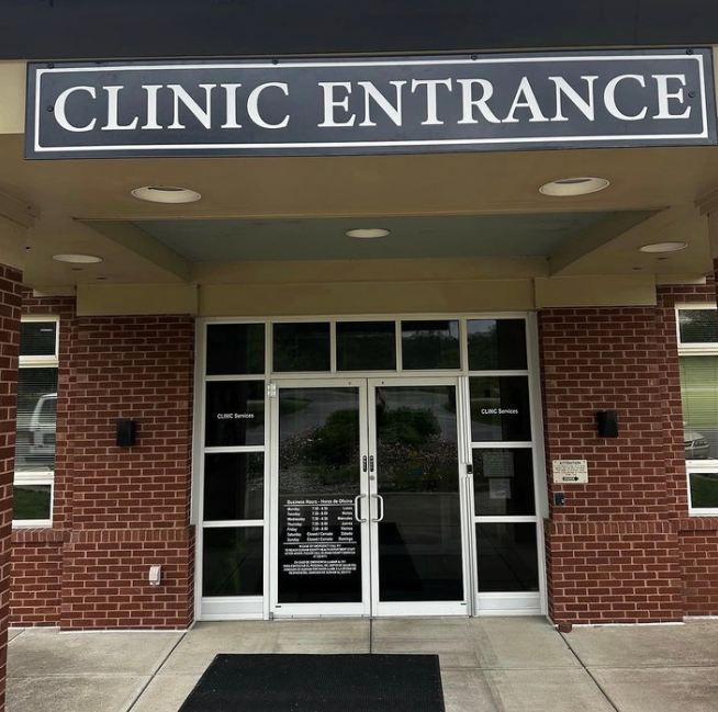 Clinic entrance with brick facade, glass double doors, and a black sign above the doorway