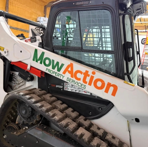 White MowAction skid steer with tracked tires inside a warehouse garage
