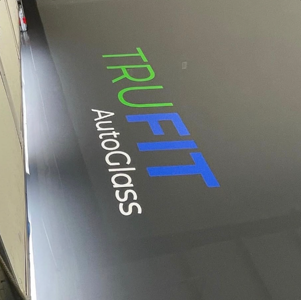 TRUFIT AutoGlass logo in green, blue, and white on a dark gray surface