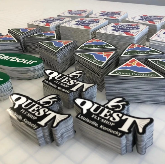 Stacks of Quest and Barbour brand promotional cards in black, green, red, and blue designs on a table